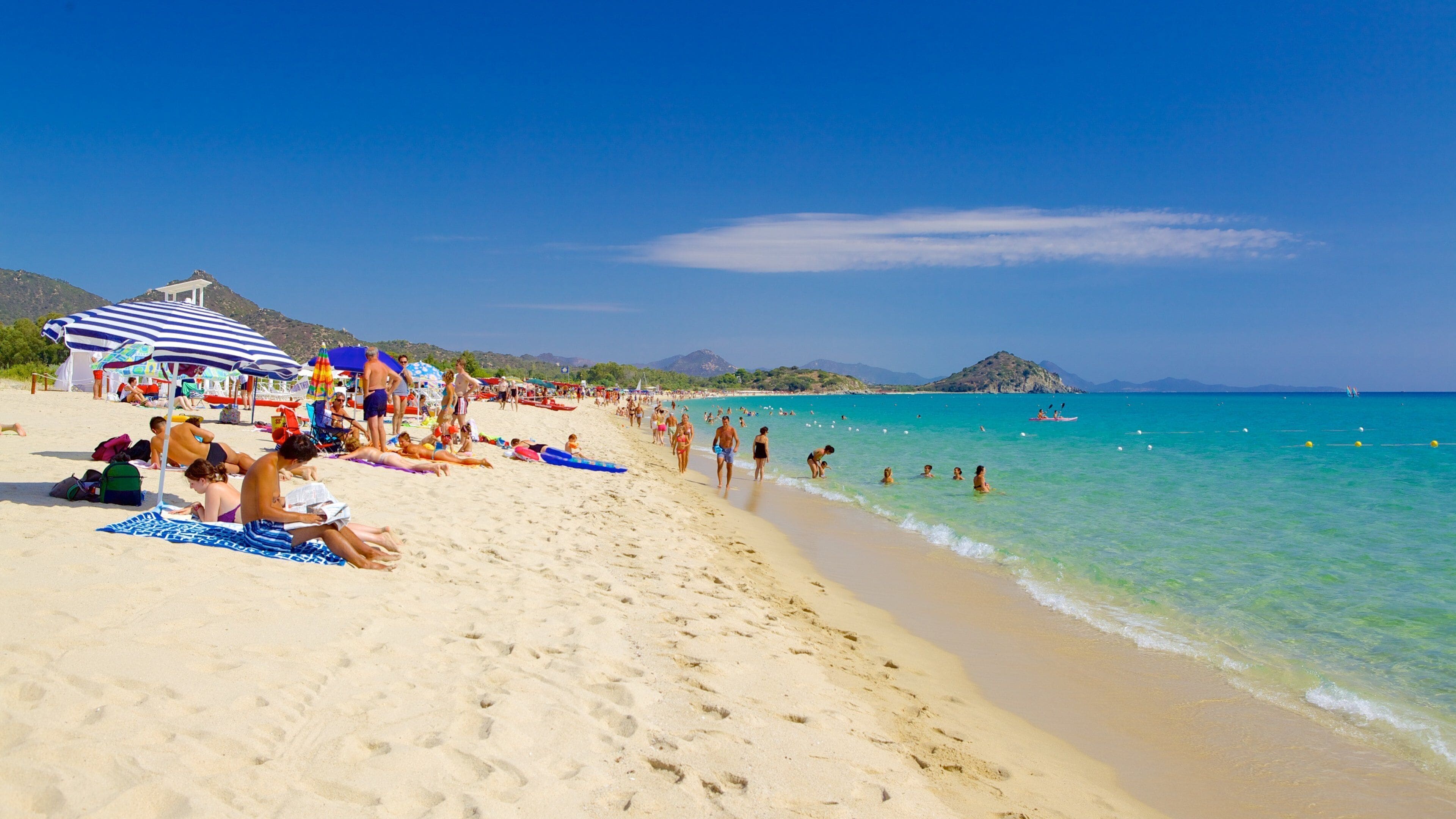 A crowded beach with people sunbathing and swimming.
