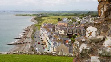 A coastal town with a stone wall, a beach, and fields in the background.