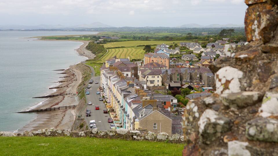 A coastal town with a stone wall, a beach, and fields in the background.