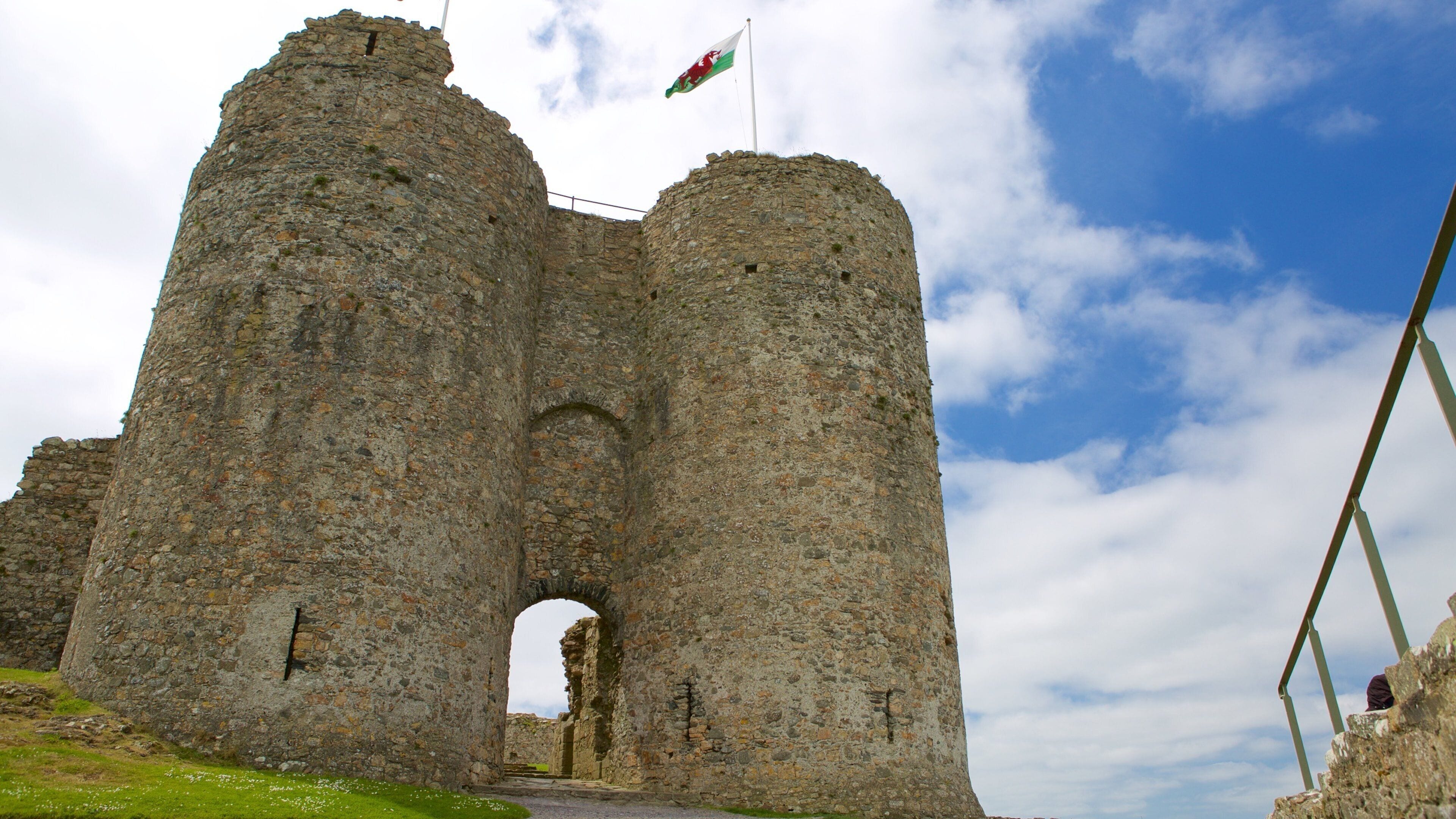 A historic stone castle with a flag, an archway entrance, and a clear sky.