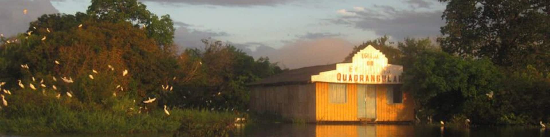 A houseboat named 'Quadrangle' on a calm river with surrounding greenery.
