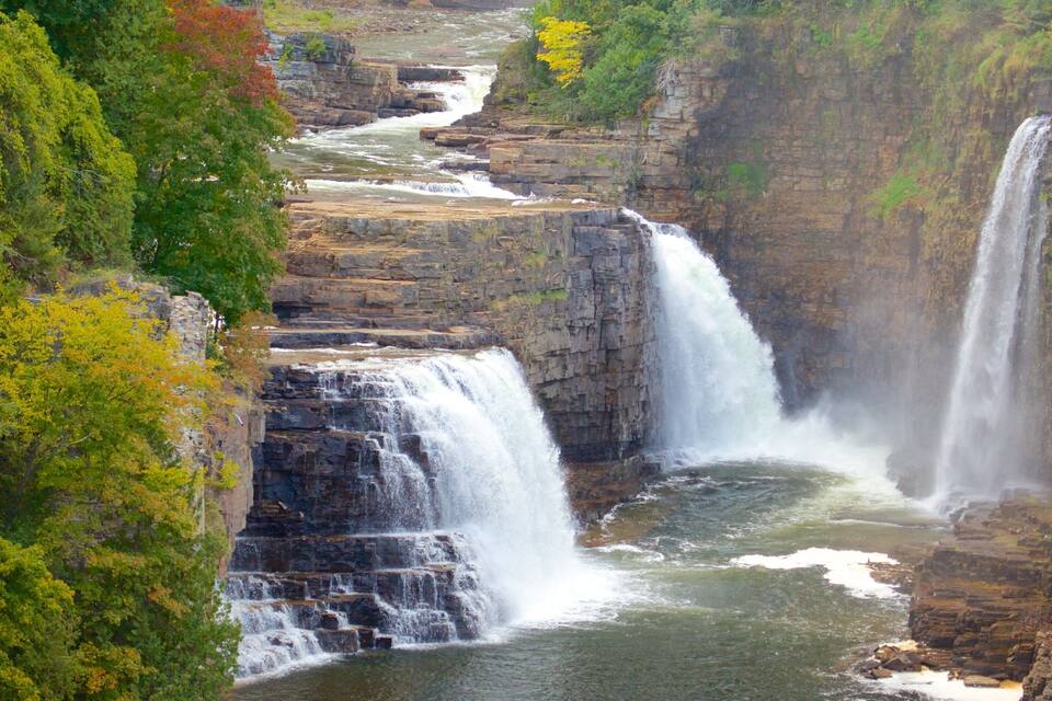 A multi-tiered waterfall cascading through a rocky gorge surrounded by autumn foliage.