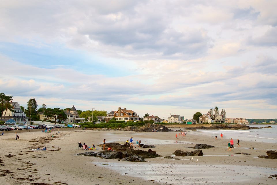 A beach with people, cars, and houses along the shore.