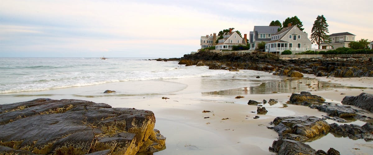 A rocky beach with houses on a cliff overlooking the ocean.