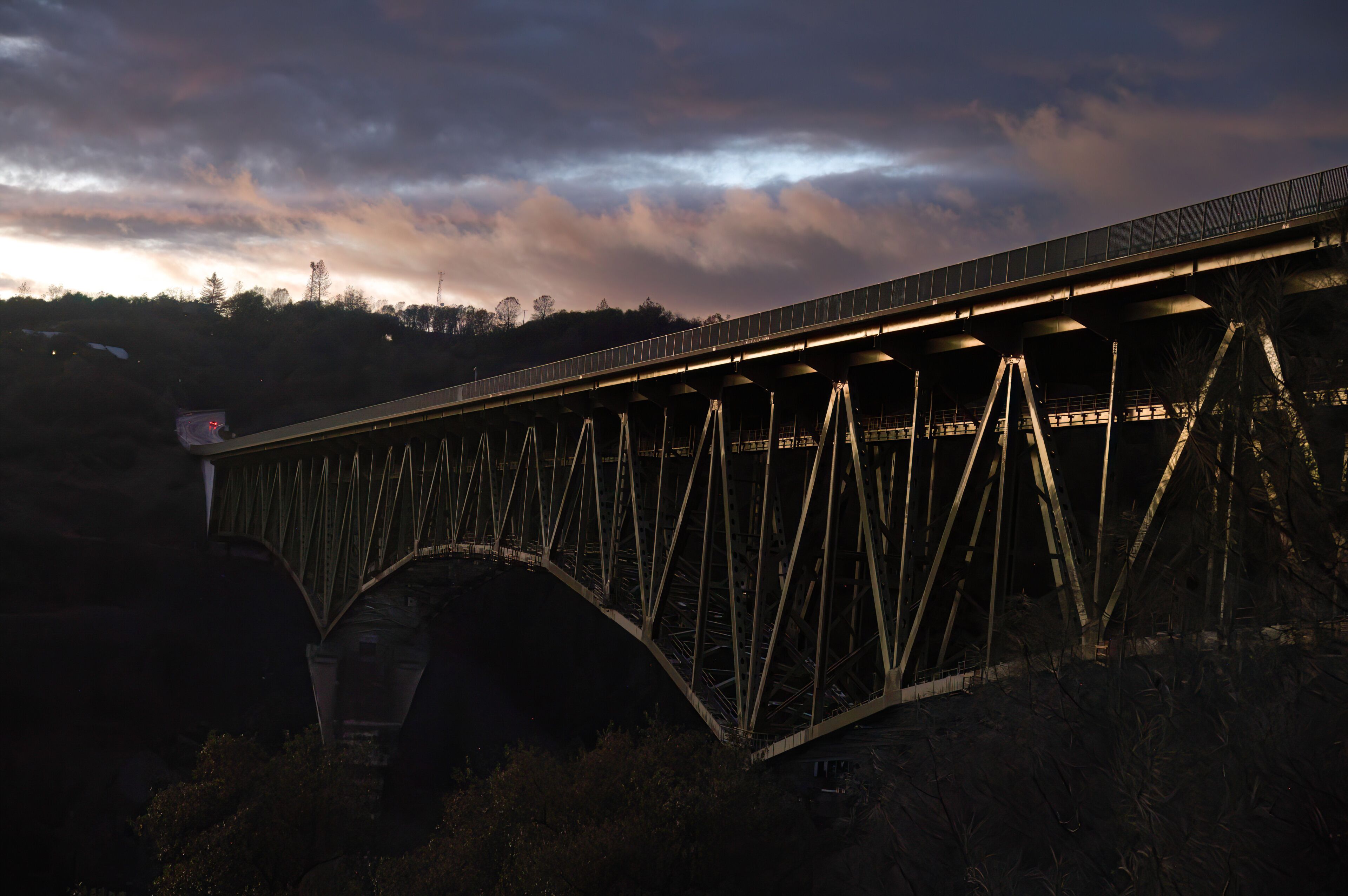 Foresthill Bridge after  sunset with dramatic storm clouds and light reflections.  It is the highest bridge in California at 730 ft. a parabolic haunched deck truss and steel cantilever bridge.