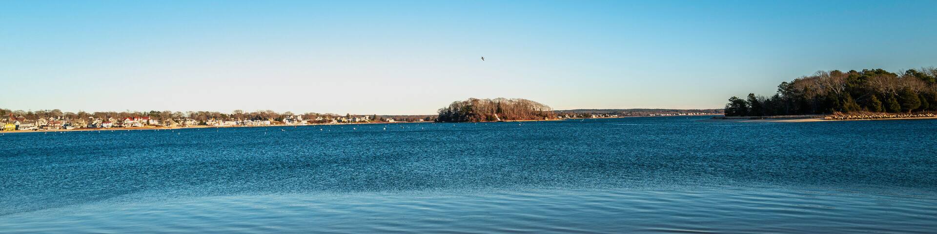 Topographical beach and ocean landscape with footprints on the sand. Tranquil sun down seascape over the Onset Bay and Beach in Onset, Massachusetts during the off-season.