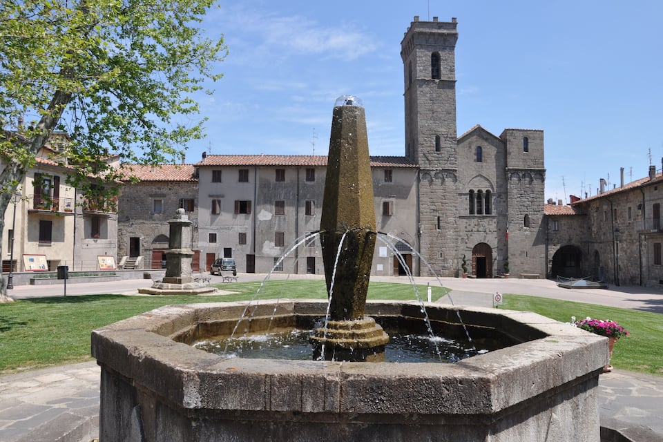 A historic building with a tower, a fountain, and a courtyard.