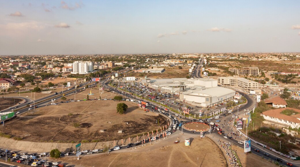 High view point cityscape of Accra, Ghana. Traffic jam on a roundabout at a shopping mall next to an highway interchange. The slums houses and buildings of Northern Accra on the background.
