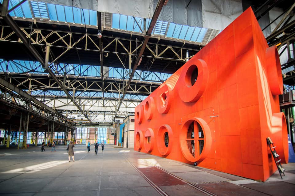 Een groot industrieel gebouw met een opvallende oranje structuur met ronde uitsparingen.
