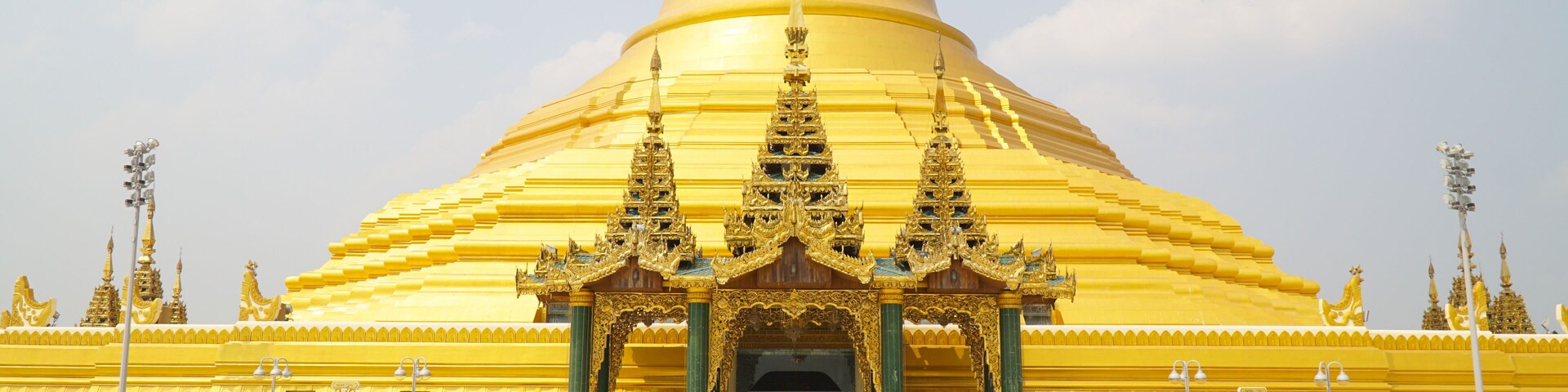 Uma grande stupa dourada com arquitetura intrincada e um pátio com telhas.