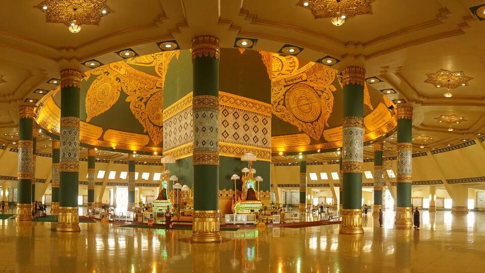A grand hall with ornate columns, intricate ceiling designs, and a central ornate structure.