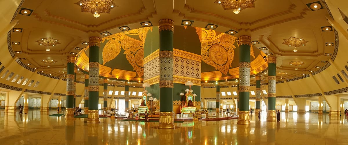 A grand hall with ornate columns, intricate ceiling designs, and a central ornate structure.