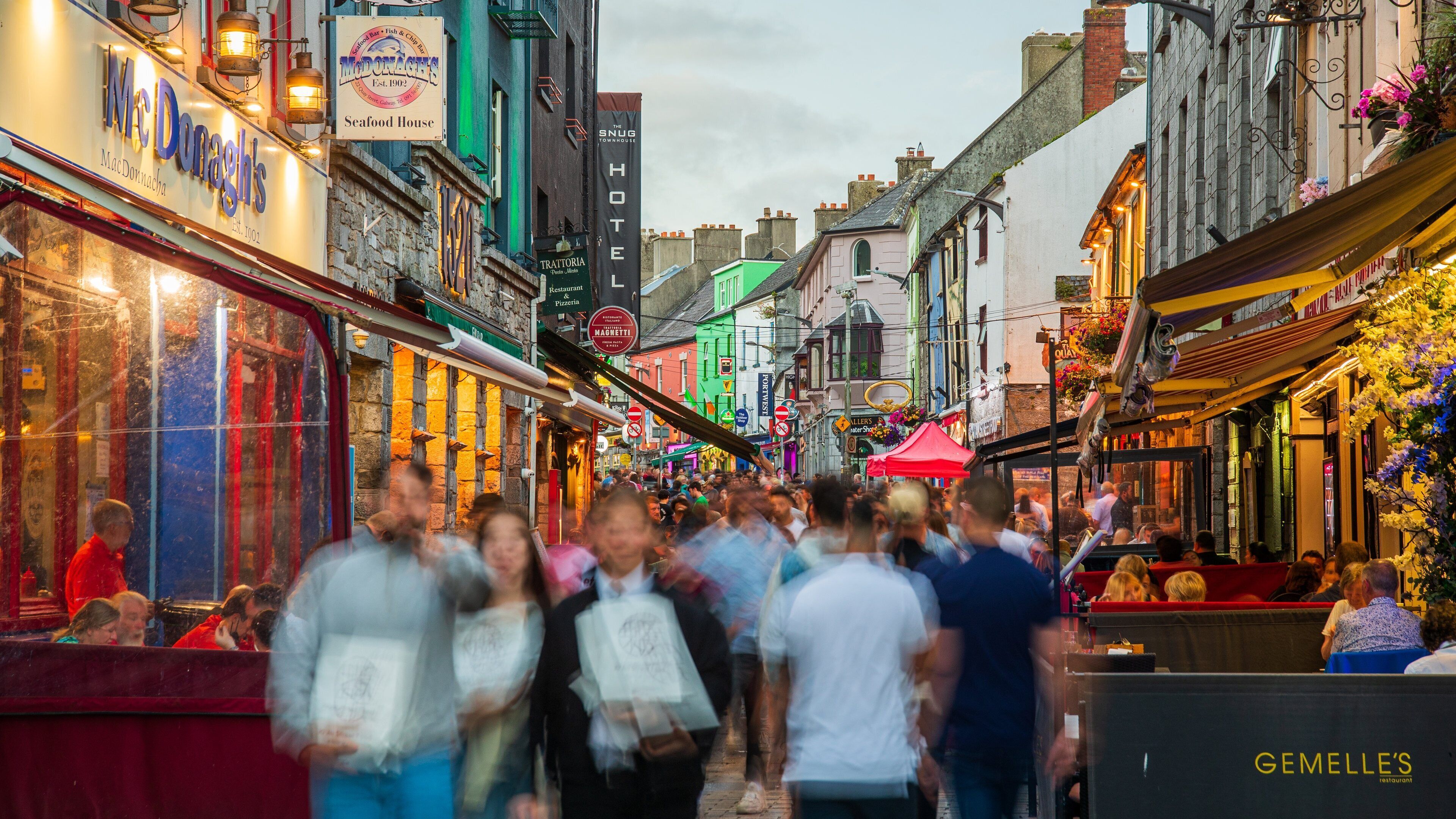A crowded street with various shops and restaurants, including McDonald's and Gemelle's.