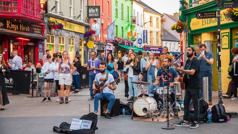 A street performance with musicians on a sidewalk in a colorful urban area.