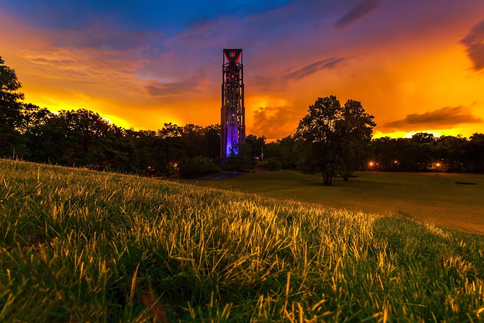 Una torre con ventanas iluminadas al atardecer.