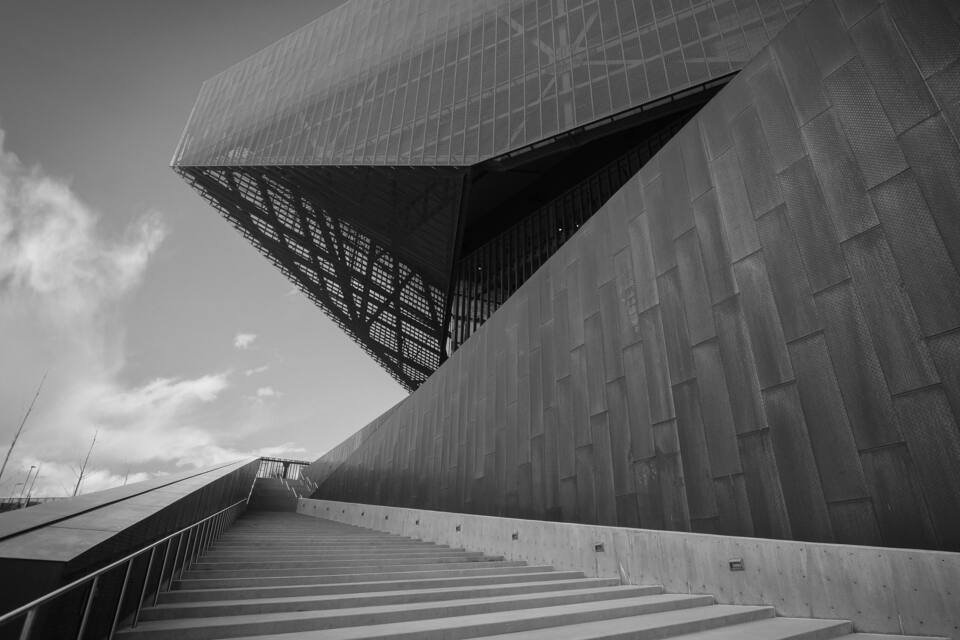 A modern architectural structure with a unique angular design and a staircase leading up to it.