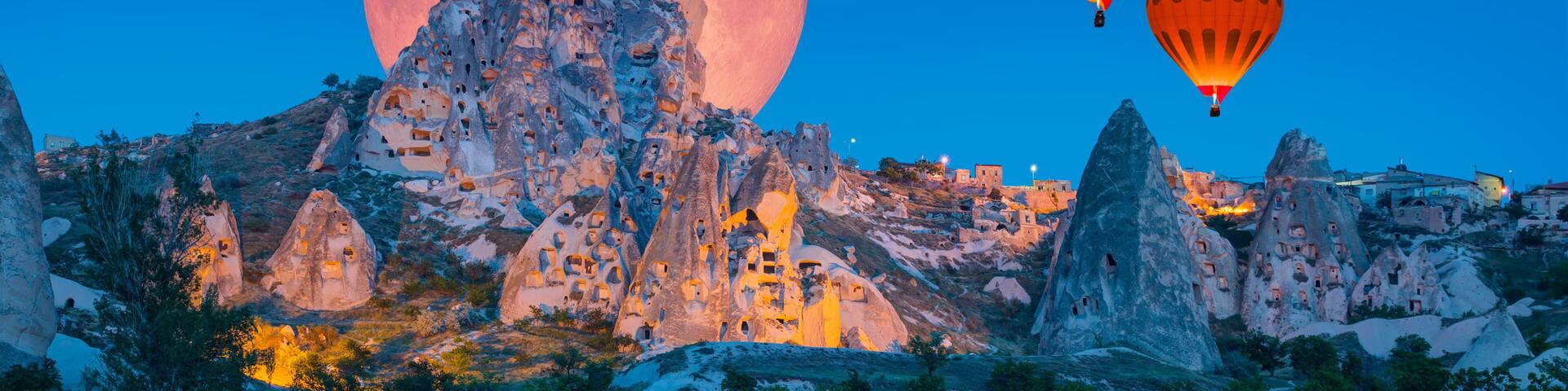 Hot air balloon flying over Uchisar castle with full moon "Elements of this image furnished by NASA "