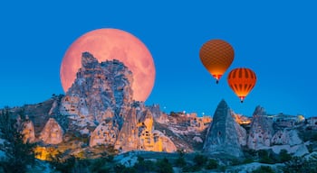 Hot air balloon flying over Uchisar castle with full moon "Elements of this image furnished by NASA "