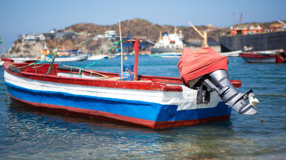 A small boat with a red and blue hull docked at a harbor.