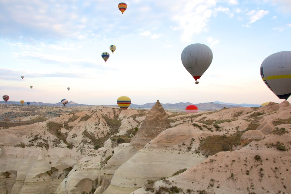 Un paisaje con numerosos globos aerostáticos volando sobre un terreno rocoso con formaciones geológicas singulares.