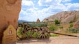 A green wooden cart with large wheels parked next to a rock with a sign indicating distances to Kizilcukur and Gavuşin.