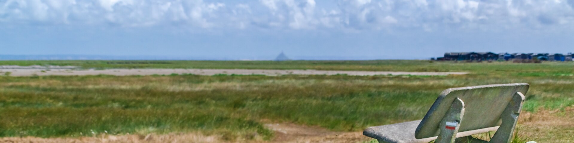 View of an empty bench with famous Mont Saint Michel in background as seen from Le Vivier-sur-mer in Normandy France