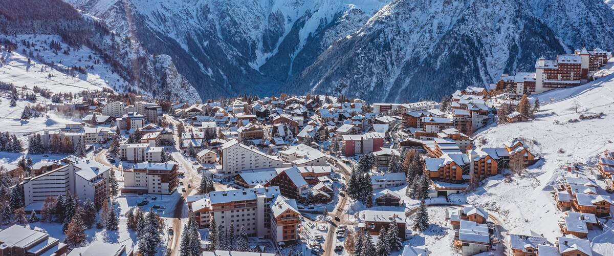 A snow-covered mountain town with buildings and ski slopes.