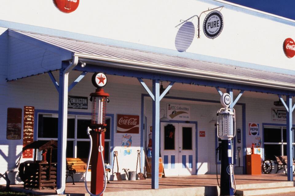 A vintage gas station with a Coca-Cola sign, a Texaco sign, and a Pure sign.