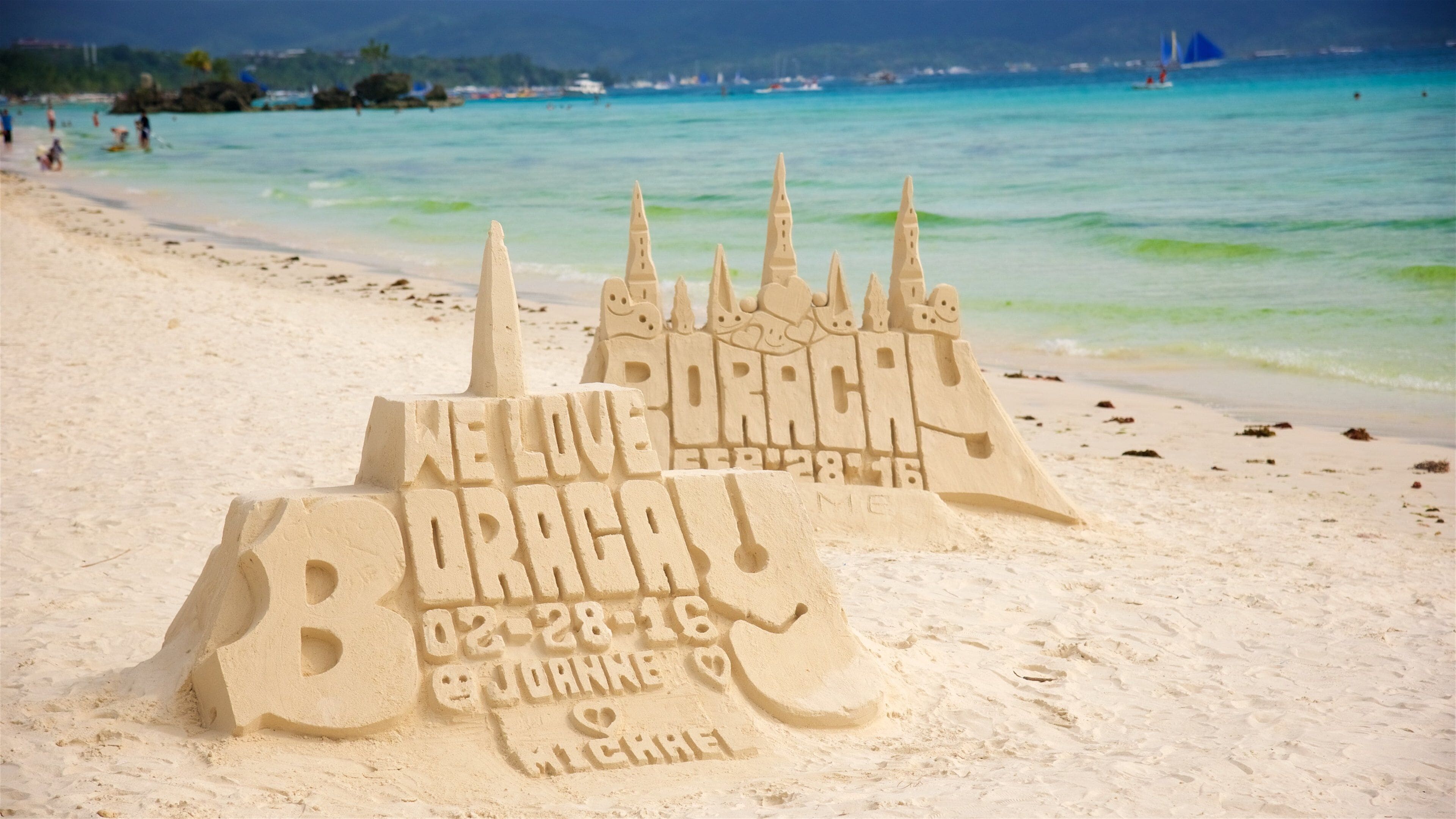 A sandcastle on a beach with a message carved into it.