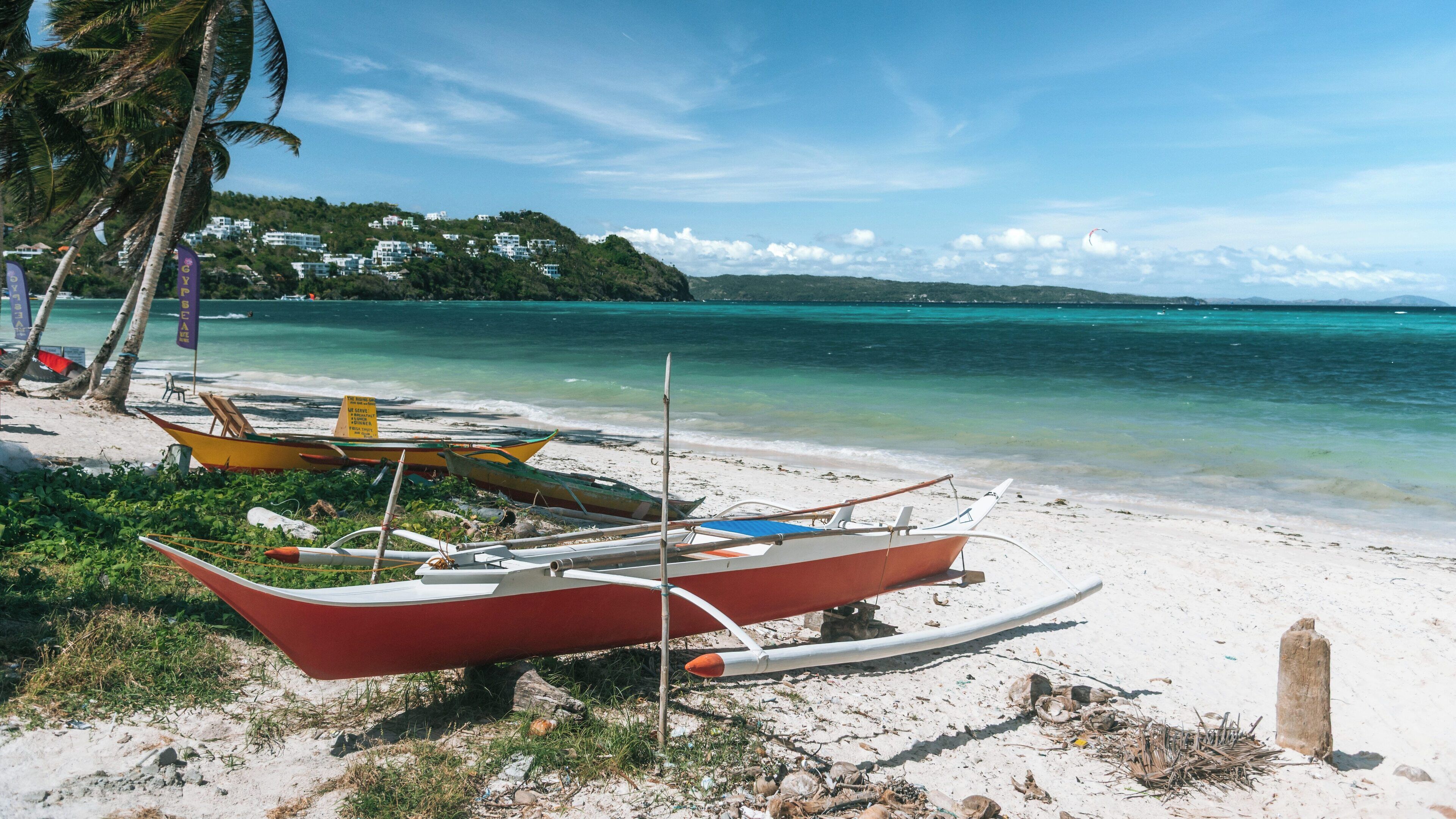 Discovering the beauty of Bulabog Beach in Boracay Island, with colorful boats and pristine waters under a bright blue sky