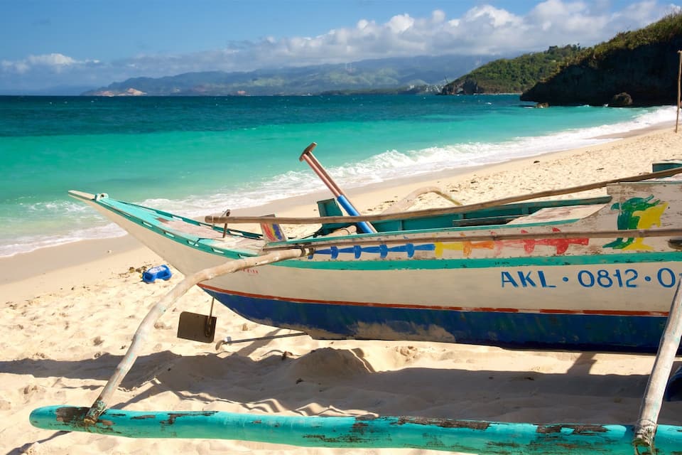 A beach with a row of colorful boats, a sandy shore, and turquoise waters.