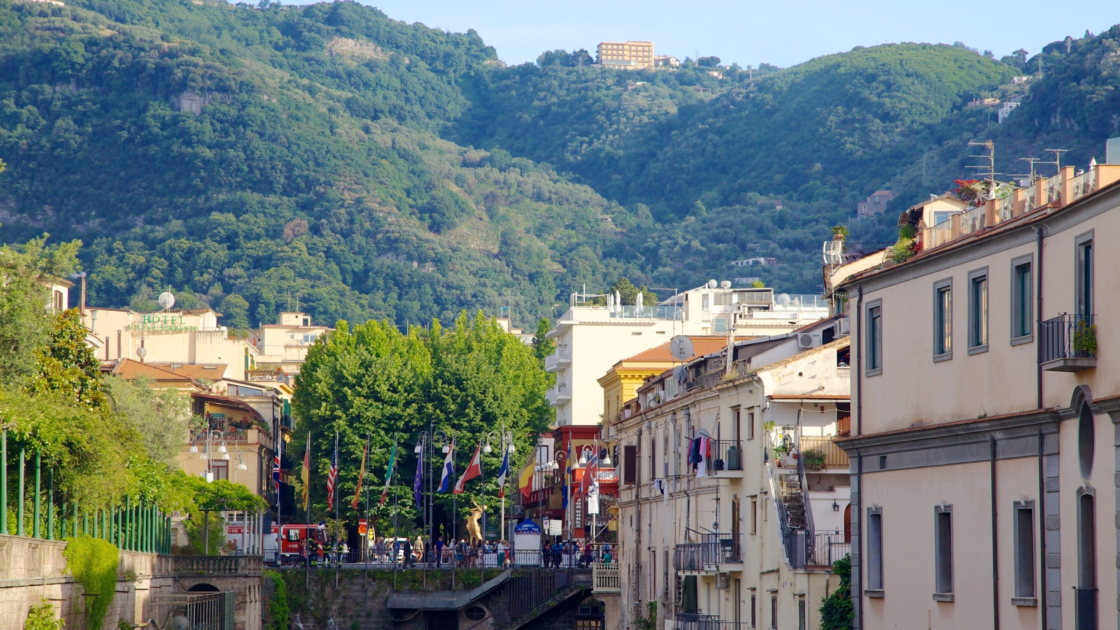 A hillside town with buildings, trees, and a prominent hilltop structure.
