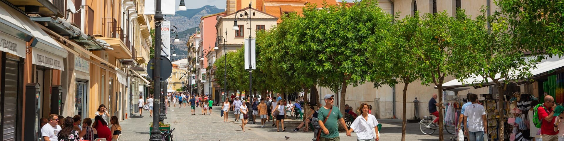 A bustling street with historic buildings, a prominent clock tower, and pedestrians.