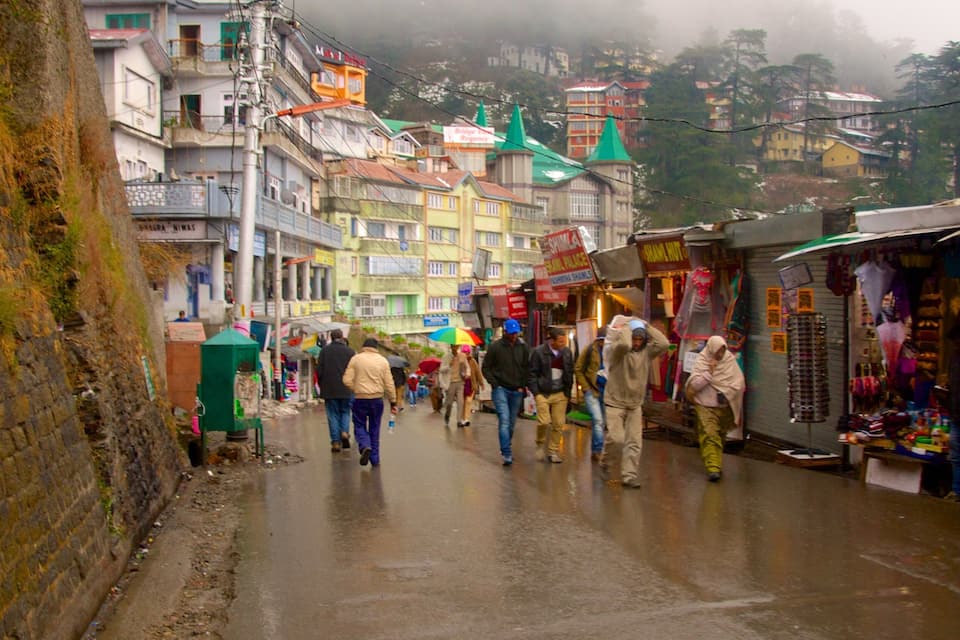 Una calle concurrida en un pueblo montañoso, con tiendas y edificios coloridos.