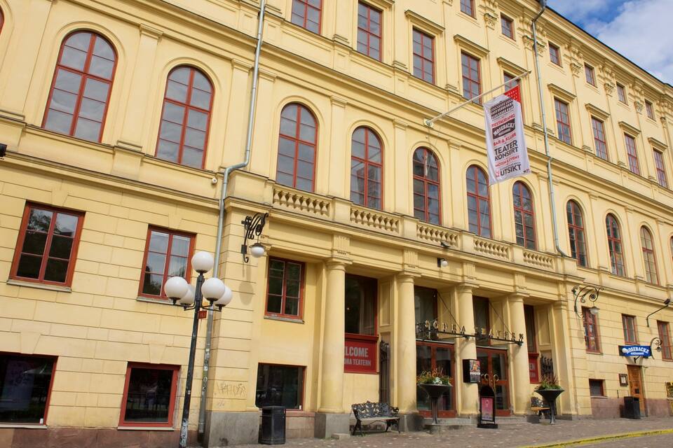 Un edificio amarillo con ventanas arqueadas y un cartel para un teatro.