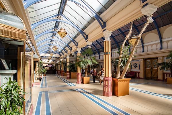 An ornate indoor atrium with high ceilings, decorative columns, and potted palm trees.