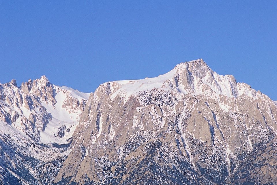 Une chaîne de montagnes enneigées, avec un paysage rocheux au premier plan.