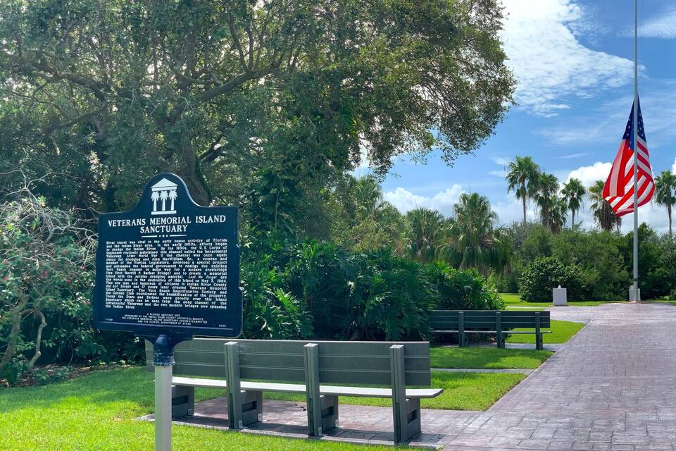 Un santuario conmemorativo para veteranos, con un asta de banderas, bancos y un sendero.