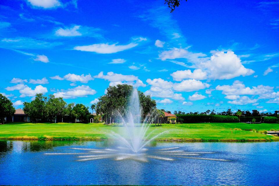 Una fuente en un parque con un cielo azul despejado y césped verde exuberante.