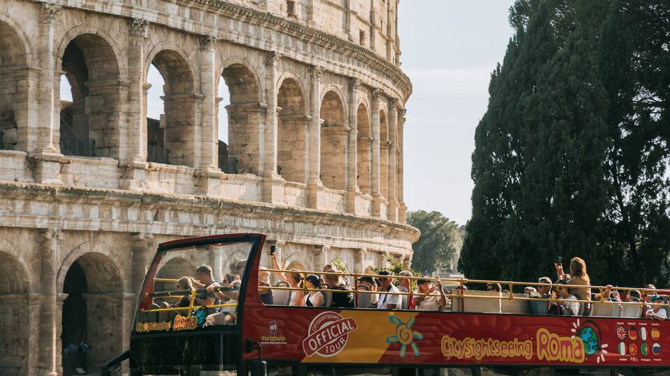 Een dubbeldekkerbus met toeristen voor het Colosseum.