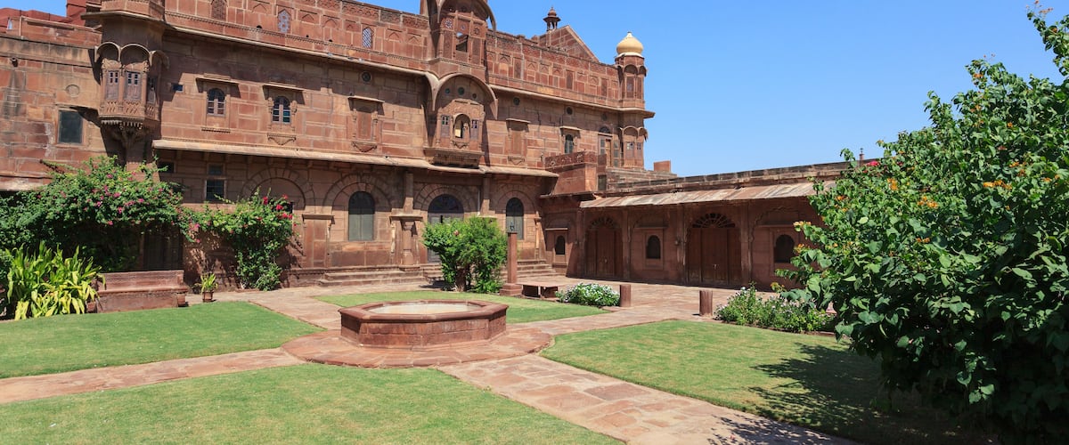 A historic building with intricate architecture, a courtyard, and lush greenery.