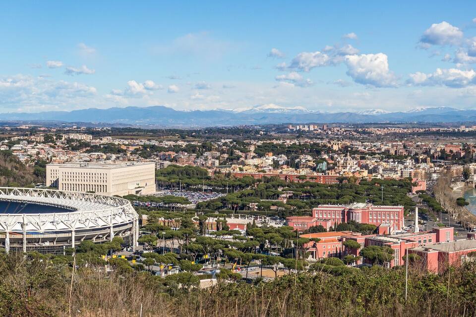 A stadium surrounded by a cityscape with mountains in the background.