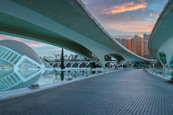 Un puente de arquitectura moderna con una piscina reflectante al frente.