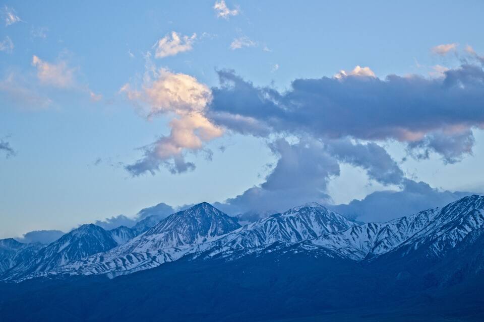Snow-covered mountains under a blue sky with scattered clouds.