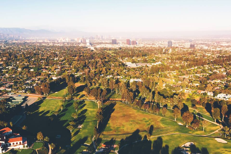 Vista aérea de una ciudad con zonas residenciales, espacios verdes y un campo de golf.