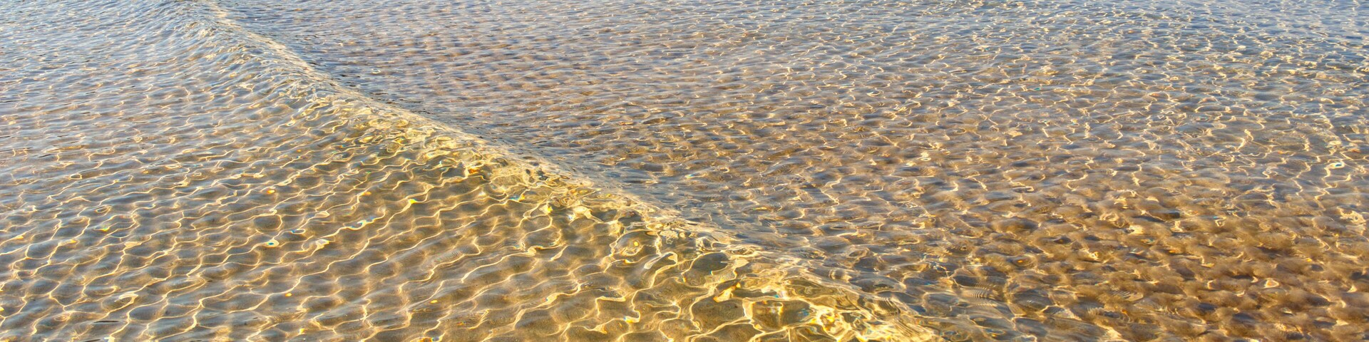Una playa despejada con aguas poco profundas y una línea de costa distante.