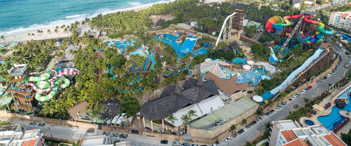A coastal resort with multiple swimming pools, water slides, and palm trees.