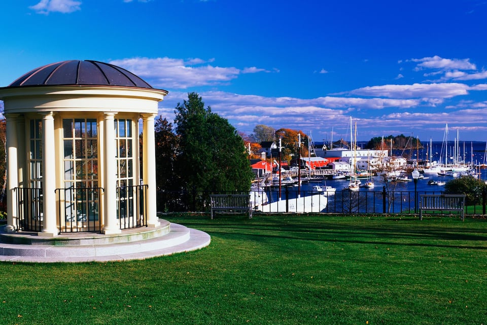 A gazebo in a park with a marina in the background.