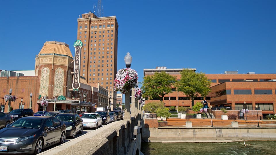 A city street with cars, a bridge, and buildings including a theater with a marquee.