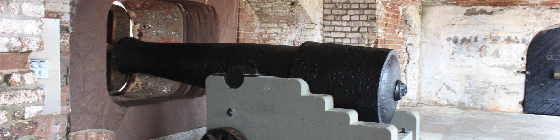 A cannon mounted on a platform in a brick structure.